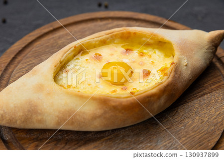 Traditional Georgian Adjarian khachapuri with eggs and cheese on a wooden board 130937899