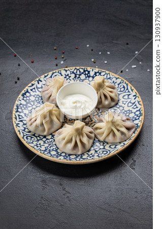 Traditional Georgian khinkali dumplings with sour cream sauce on ceramic plate 130937900