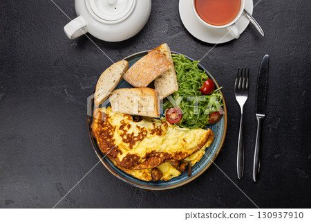 Healthy breakfast with omelet, ciabatta, salad and tea on dark stone background Healthy breakfast with omelet, ciabatta, salad and tea on dark stone background 130937910