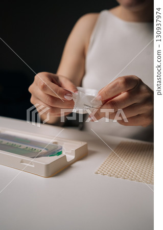 Close-up of woman opening cleaning wipe to prepare smartphone for screen protector installation, ensuring clean and dust-free surface for optimal adhesion. Concept of mobile phone maintenance 130937974