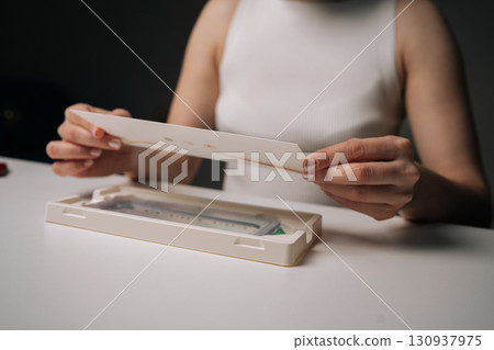 Close-up of woman opening screen protector kit, preparing to install protective glass film on smartphone, ensuring protection against scratches and damage. Concept of mobile phone maintenance 130937975