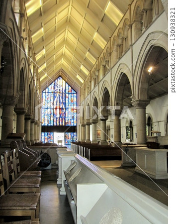 The cathedral's aisle, lit by gorgeous stained glass The cathedral's aisle, lit by gorgeous stained glass 130938321