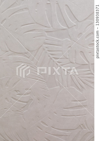 Textured wall featuring leafy patterns in a light color, enhancing a calm and natural atmosphere 130938371