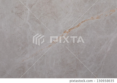 Marble surface featuring subtle pink tones and a prominent gold vein in a natural setting Marble surface featuring subtle pink tones and a prominent gold vein in a natural setting 130938635