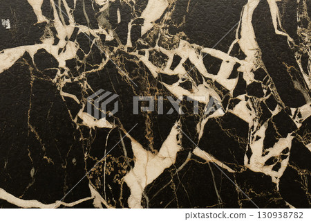 Beautiful black marble surface with white and gold veining patterns showcasing natural elegance and 130938782