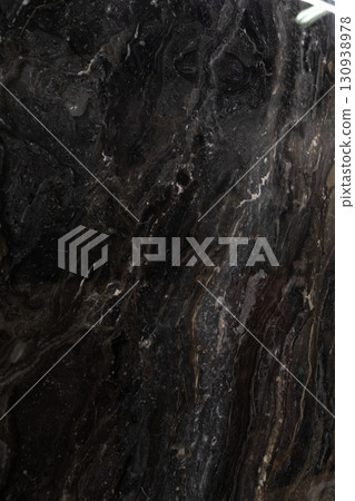 Dark marble surface showcasing elegant swirls and textures in a modern interior setting Dark marble surface showcasing elegant swirls and textures in a modern interior setting 130938978