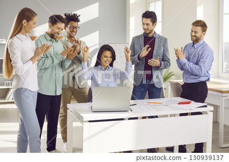 Business colleagues celebrating success looking at notebook screen Business colleagues celebrating success looking at notebook screen 130939137