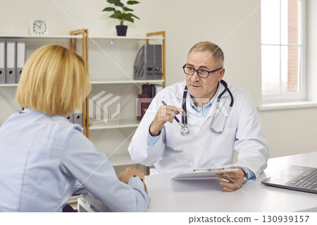 Young woman having consultation with mature male doctor in medical office Young woman having consultation with mature male doctor in medical office 130939157