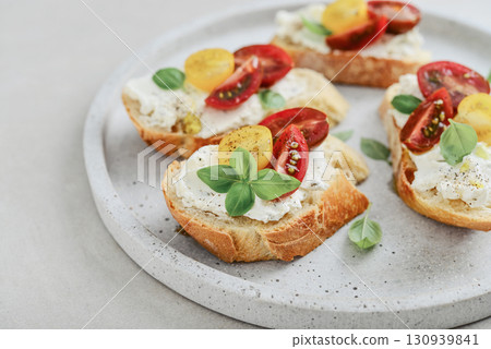 Bruschetta sandwiches with tomatoes, cream cheese, olive oil and basil on a plate Bruschetta sandwiches with tomatoes, cream cheese, olive oil and basil on a plate 130939841