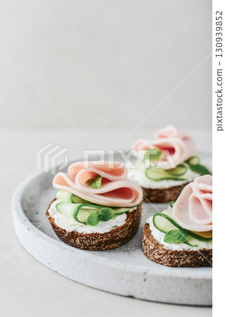 Bruschetta with baguette, bacon or meat, cream cheese, oregano and fresh cucumber 130939852