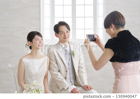 Bride and groom taking photos with friends on smartphone Bride and groom taking photos with friends on smartphone 130940047