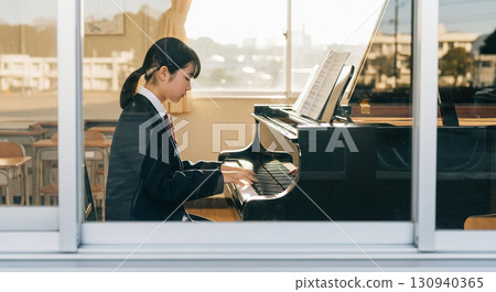 一名女高中生在音樂室彈鋼琴,這是用長焦距鏡頭從校舍外面的窗戶拍攝的 一名女高中生在音樂室彈鋼琴,這是用長焦距鏡頭從校舍外面的窗戶拍攝的 130940365