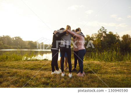 Group of people in sportswear standing in a circle hugging each other after sport workout. Group of people in sportswear standing in a circle hugging each other after sport workout. 130940590