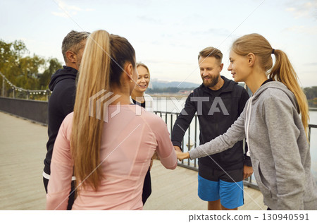 Group of happy friends high fiving each other during outdoor fitness workout in park 130940591