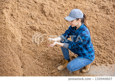 Female farmer checking quality of beer bagasse in storage area outdoors Female farmer checking quality of beer bagasse in storage area outdoors 130940607