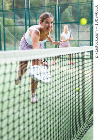 Girl playing padel tennis match during training on court Girl playing padel tennis match during training on court 130940616