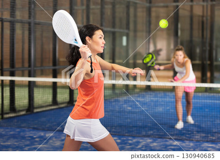 Sporty asian woman playing padel on indoor court Sporty asian woman playing padel on indoor court 130940685