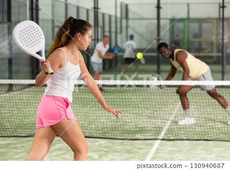 Sporty girl playing padel on indoor court, ready to hit ball 130940687