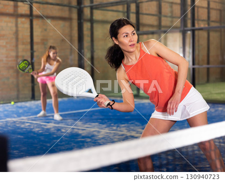 Focused woman playing paddle ball on closed court Focused woman playing paddle ball on closed court 130940723