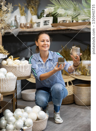 Positive woman chooses Christmas gifts in gift shop 130940735