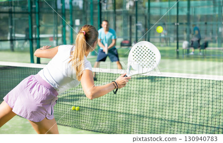 European woman tennis player in padel tennis playing on the outdoor court 130940783