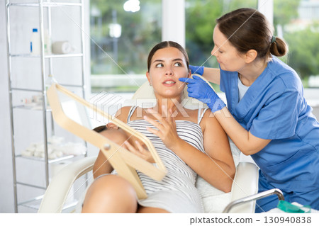 Adult female cosmetologist examining face of female patient 130940838