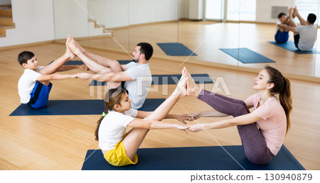Kids and parents touching each other feet on yoga training Kids and parents touching each other feet on yoga training 130940879