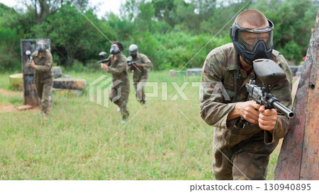 Portrait of man with gun in camouflage on paintball field 130940895