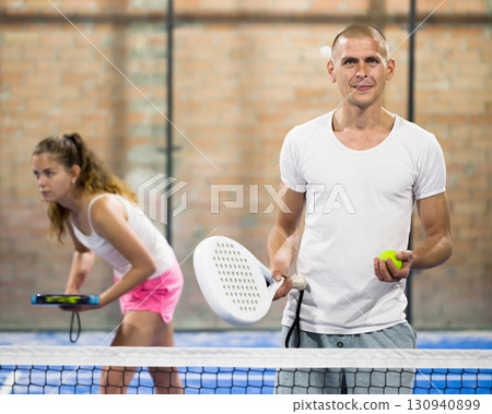 Portrait of sporty male with padel racket at court Portrait of sporty male with padel racket at court 130940899