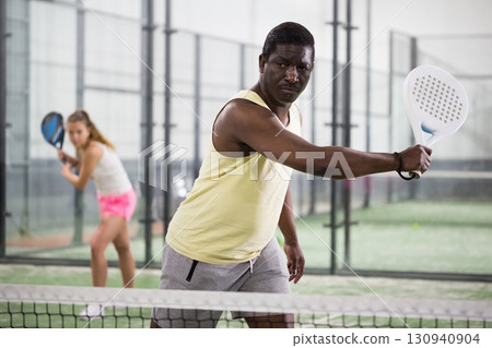 African American hitting backhand during paddle match in close court 130940904