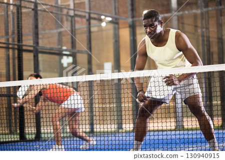 Sporty afro american man playing padel tennis indoor Sporty afro american man playing padel tennis indoor 130940915