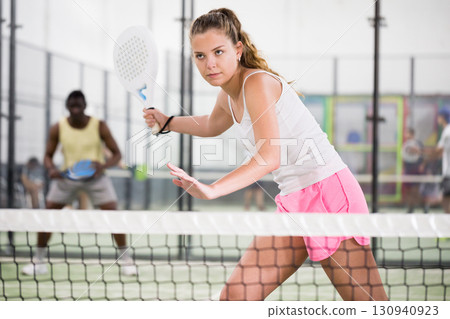 Concentrated energetic girl playing paddle tennis indoors 130940923