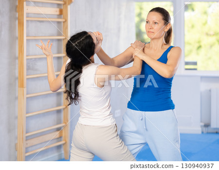 Active woman with professional female trainer are training captures on self-defense course in gym Active woman with professional female trainer are training captures on self-defense course in gym 130940937