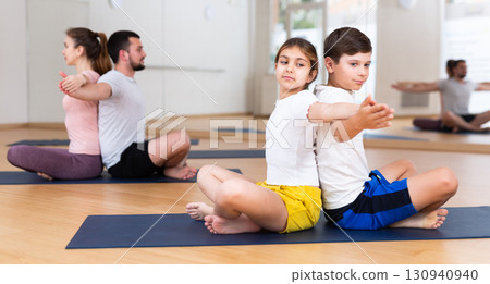 Kids and parents sitting back to back on mats 130940940