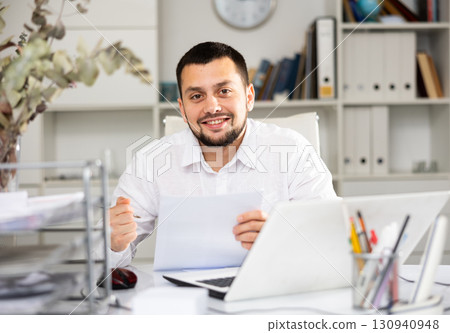 Smiling businessman doing his daily work in office Smiling businessman doing his daily work in office 130940948