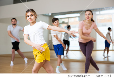 Girl dancing modern dance with family in gym 130940951