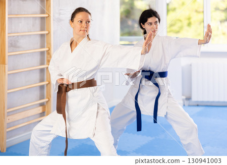 Women in kimono trying martial moves at karate class Women in kimono trying martial moves at karate class 130941003
