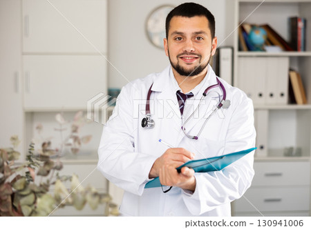 Portrait of positive male doctor with folder Portrait of positive male doctor with folder 130941006
