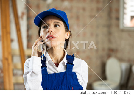 Woman builder using smartphone while standing in renovated room Woman builder using smartphone while standing in renovated room 130941052
