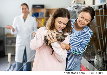 Preteen girl with mother visiting animal shelter to take home kitten 130941090