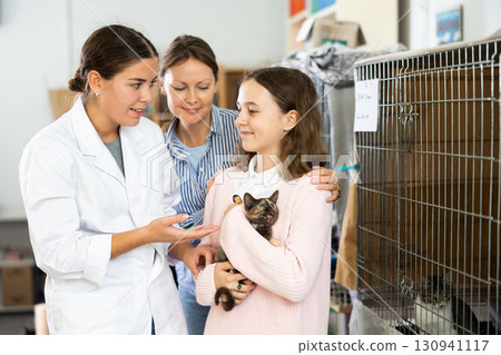 Female volunteer talking to family choosing kitten for adoption Female volunteer talking to family choosing kitten for adoption 130941117