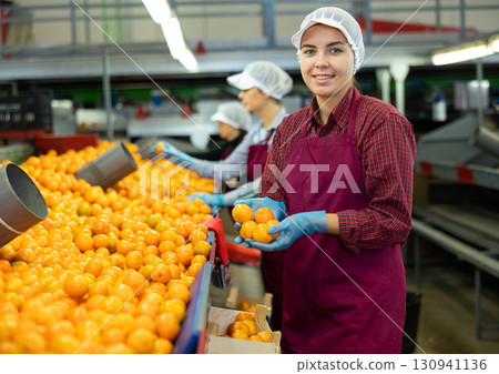 Smiling young girl working on mandarins sorting factory Smiling young girl working on mandarins sorting factory 130941136