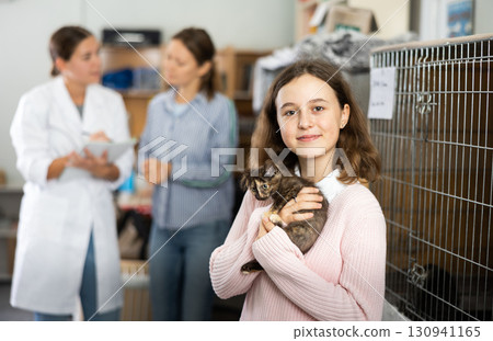Preteen girl standing in animal shelter with kitten in hands Preteen girl standing in animal shelter with kitten in hands 130941165