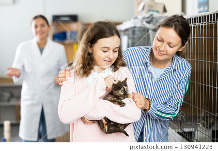 Preteen girl with mother visiting animal shelter to take home kitten Preteen girl with mother visiting animal shelter to take home kitten 130941223