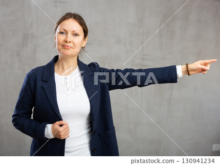 Smiling adult woman in jacket gesturing in studio Smiling adult woman in jacket gesturing in studio 130941234
