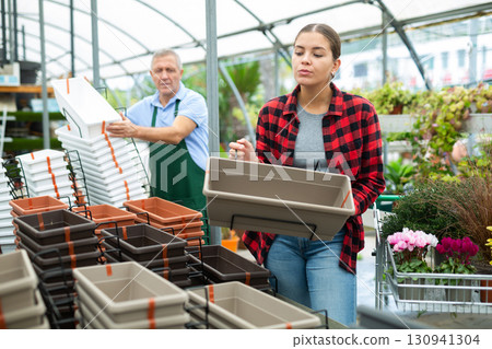 Joyful young woman choosing flower pots during shopping in a garden market 130941304