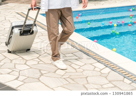 Vacation, young Asian man traveling alone walking with carry-on suitcase by the pool at a resort 130941865