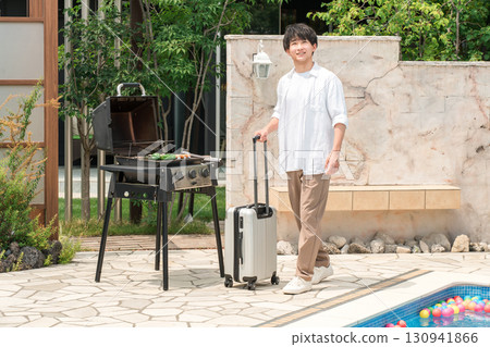 Vacation, young Asian man walking with carry-on suitcase by the pool at a resort Vacation, young Asian man walking with carry-on suitcase by the pool at a resort 130941866