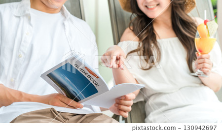 Couple sitting on poolside chairs at a resort hotel on a trip 130942697