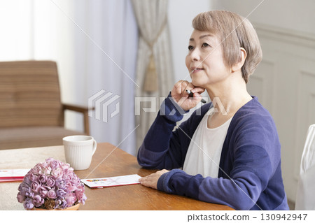 A senior woman writing the address on a gift envelope with a brush pen 130942947